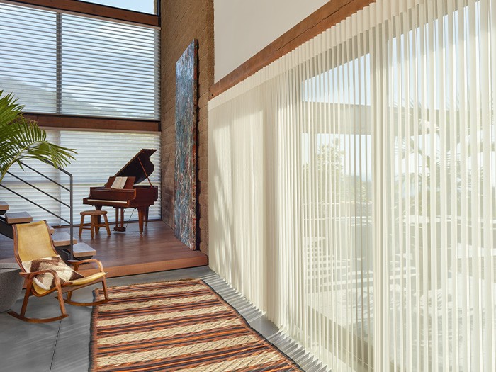 rocking chair and piano near large windows