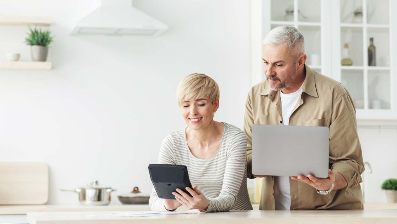 Manage finances bills tax, planning, consider budget. Smiling adult couple with laptop and calculator talk, doing paperwork together at home, discuss family mortgage loan money payment in kitchen